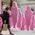 A woman walking by a line of pink cutouts in honor of the fight against breast cancer