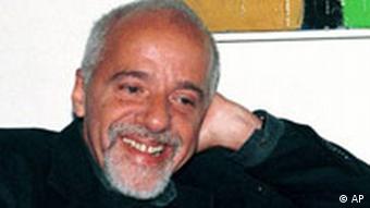 Paulo Coelho lächelt, mit dem Arm aufgestützt (Pressefoto)
