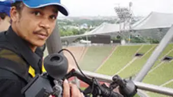Video journalist with camera in a stadium