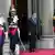 Sarkozy stands outside the Elysee Palace with three ceremonial guards