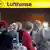 Passengers stand before a Lufthansa ticketing counter