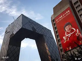 The new China Central Television (CCTV) headquarters building is seen under construction next to a giant advertisement promoting the Beijing Olympic Games in Beijing, Wednesday July 16, 2008. The spectacular 230 meter (755 foot) building is one of a series of landmarks, notable for their futuristic design, that will greet visitors to the Olympic Games, which open Aug. 8. (AP Photo/Andy Wong)