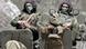 Two Russian solders with their faces covered sit on a tank Two Russian solders with their faces covered sit on a tank