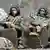 Two Russian solders with their faces covered sit on a tank