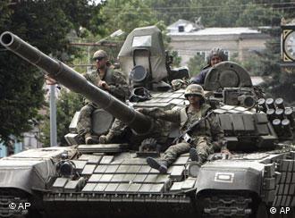 Georgian soldiers sit atop a tank as it moves along a street in Gori, Georgia