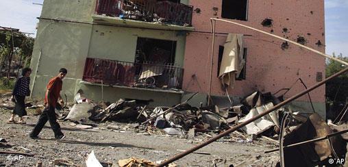 Local residents pass by a damaged building in Gori, Georgia