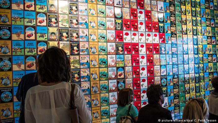 People standing in front of a wall covered with Tintin book covers