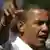 Barack Obama sa mikrofonom i podignutom desnom rukom.