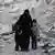 Женщина с двумя детьми посреди обломков в Алеппо