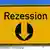 A yellow sign reading 'Rezession' with arrow pointing downwards