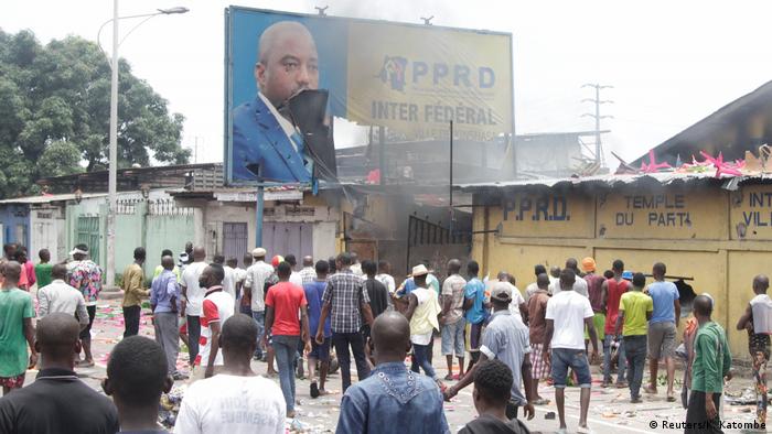 Congolese opposition supporters chant slogans as they destroy the billboard of President Joseph Kabila