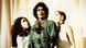 A still from the film 'Rocky Horror Picture Show': a character dressed as parody of doctor with two women looking up at him, wearing face masks. A still from the film 'Rocky Horror Picture Show': a character dressed as parody of doctor with two women looking up at him, wearing face masks.
