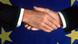 Two hands shaking before an EU flag Two hands shaking before an EU flag