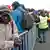 Refugiados na fila de registro durante evacuação do acampamento ilegal conhecido por "Selva de Calais"
