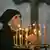 Женщина ставит зажженую свечу перед иконой в православном храме