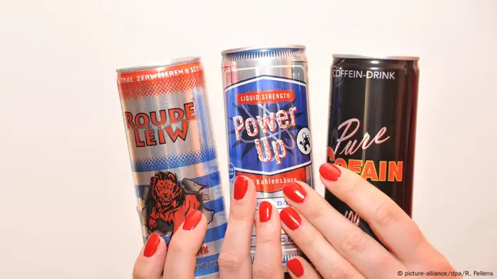 Zwei Hände mit lackierten Fingernägeln halten mehrere Energy-Drinks (picture-alliance/dpa/R. Fellens)