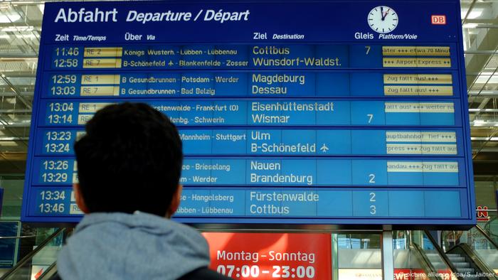 A man looks at a board at a train station