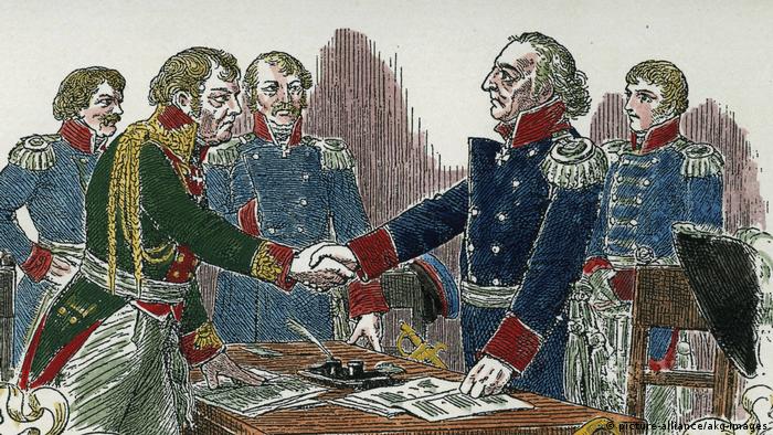 александровка в германии история. 36330057 303. александровка в германии история фото. александровка в германии история-36330057 303. картинка александровка в германии история. картинка 36330057 303. В северной части Потсдама есть место столь русское, какой даже сама Россия никогда не была. Тринадцать типично русских изб, щедро украшенных резьбой, стоят здесь одна возле другой и позади каждой — большой фруктовый сад. Некоторые дома красуются в несколько этажей, а те, что поскромнее, рассредоточены по краям. Кто-то торгует здесь огурцами, кто-то — яблоками. В затесавшемся меж построек кафе подают солянку. Построены эти дома были в 1826 году. Аутентичными они не были никогда.Поселок называется Александровкой, поскольку построен по приказу прусского короля Фридриха Вильгельма III в память о царе Александре I, которым его связывали переменчивые отношения — они были и друзьями, и врагами. В 1812 году король Пруссии взял в плен 62 русских солдата и доставил в Потсдам. Говорят, его тронули их меланхоличные напевы,они стали его солдатским хором и сопровождали прусское войско, развлекая его «песнями с тамбурином и маленькими колокольчиками». Когда Россия и Пруссия стали друзьями, солдаты так и остались при королевском дворе в Потсдаме — царь преподнес их Фридриху Вильгельму в качестве подарка. Ради оставшейся дюжины человек и построили Александровку. Ансамбль срубов, украшенных резными орнаментами, флюгерами, зубчатыми фризами. Этот фронтон принадлежит самому великолепному дому в центре поселка — в нем жил смотритель колонии.Король лично разработал вместе с Петером Йозефом фон Ленне план поселка, имеющий форму ипподрома, рассеченного Андреевским крестом; часть домов стоят напротив друг друга, другие на большом расстоянии.Каждый из певцов русского солдатского хора получил собственный дом со всем хозяйством — вплоть до глиняных горшков, огромным садом, огородом и коровой. От уплаты налогов они были освобождены. Идея была возвышенной, вот только не слишком функциональной. Солдаты не были крестьянами, они не могли себя обеспечивать, прилично выпивали и все чаще слали просительные письма. Вскоре им было разрешено зарабатывать деньги иначе: они стали сдавать комнаты тем берлинцам, что летом стремились попасть в иной, фольклорный мир.За каждым домом простирается большой участок, с которого солдатские певцы должны были кормиться.Курьез не только в том, что в социальном плане поселок не действовал. По сути, в нем есть что-то от Диснейленда; это не русская, а потемкинская деревня: сами срубы таковыми не являются, а представляют собой фахверковые дома, обитые деревом. Деревянная резьба не является традиционно крестьянской, а берет свое начало, скорее, в романтических идеях XIX века. Ее прообразом послужила другая образцовая деревня под Санкт-Петербургом — Глазово. Даже членение чудесного фасада не аутентично и не практично: там, где обозначен главный вход, войти в дом, как правило, невозможно — можно только сбоку. Так что не всегда можно выйти прямо на веранду. Не случайно позднее баварский Король Людвиг II построил Нойшванштайн, идеализированный рыцарский замок: романтика, идеализация сельской жизни и средневековья оставили отпечаток на времени и его искусствах. Так что Александровка соотносится не столько с Россией, сколько с эпохой, в которую возникла.Так выглядела деревня между 1928 и 1944 годами, запечатленная Максом Бауэром.В то время, как одни дома имеют два этажа, другие (особенно те, что по краям поселка) выглядят скромнее. Принцип, однако, один и тот же: имитация сруба и традиционного декора плюс фантазия.На холме возвышается выкрашенный в умилительный розовый цвет православный храм Александра Невского, построенный вместе с поселком и для него предназначенный. Внутри мерцают русские иконы, пахнет ладаном и звучит запись мужского хора.Некогда Александровка была популярным туристическим объектом, но со временем дела пошли все хуже. Хотя архитектурный ансамбль еще во времена ГДР был взят под охрану памятников, сохранился он плохо. Отдельные дома постепенно пришли в упадок, территория заросла, была застроена садовыми домиками. Позже через деревню чуть было не проложили трамвайную линию — сейчас она ее огибает.После объединения Германии инициативы по охране памятников докатились и до деревни. В одном из домов был открыт музей, снова были вытащены на свет божий старинные планы Ленне. Вместо 574 старых фруктовых деревьев были посажены новые. В роскошном доме смотрителя сегодня обосновалось кафе. Большинство домов стали частными — в трех из них до 2013 года еще жили потомки тех самых певцов солдатского хора (с давних пор эти дома не разрешается продавать, а только передавать по наследству, причем по прямой мужской линии). В одном из домов был создан чудесный маленький музей. Так что сегодня Александровка снова превратилась в нарядную идиллию. В жаркие летние дни случается непомерно широкому туристическому автобусу проехать по длинным и обычно пустынным улицам, пересекающимся в виде Андреевского креста. В остальном кажется, что время здесь остановилось. Но это, в сущности, время, которого никогда не было. александровка в германии история. 36330057 303. александровка в германии история фото. александровка в германии история-36330057 303. картинка александровка в германии история. картинка 36330057 303. В северной части Потсдама есть место столь русское, какой даже сама Россия никогда не была. Тринадцать типично русских изб, щедро украшенных резьбой, стоят здесь одна возле другой и позади каждой — большой фруктовый сад. Некоторые дома красуются в несколько этажей, а те, что поскромнее, рассредоточены по краям. Кто-то торгует здесь огурцами, кто-то — яблоками. В затесавшемся меж построек кафе подают солянку. Построены эти дома были в 1826 году. Аутентичными они не были никогда.Поселок называется Александровкой, поскольку построен по приказу прусского короля Фридриха Вильгельма III в память о царе Александре I, которым его связывали переменчивые отношения — они были и друзьями, и врагами. В 1812 году король Пруссии взял в плен 62 русских солдата и доставил в Потсдам. Говорят, его тронули их меланхоличные напевы,они стали его солдатским хором и сопровождали прусское войско, развлекая его «песнями с тамбурином и маленькими колокольчиками». Когда Россия и Пруссия стали друзьями, солдаты так и остались при королевском дворе в Потсдаме — царь преподнес их Фридриху Вильгельму в качестве подарка. Ради оставшейся дюжины человек и построили Александровку. Ансамбль срубов, украшенных резными орнаментами, флюгерами, зубчатыми фризами. Этот фронтон принадлежит самому великолепному дому в центре поселка — в нем жил смотритель колонии.Король лично разработал вместе с Петером Йозефом фон Ленне план поселка, имеющий форму ипподрома, рассеченного Андреевским крестом; часть домов стоят напротив друг друга, другие на большом расстоянии.Каждый из певцов русского солдатского хора получил собственный дом со всем хозяйством — вплоть до глиняных горшков, огромным садом, огородом и коровой. От уплаты налогов они были освобождены. Идея была возвышенной, вот только не слишком функциональной. Солдаты не были крестьянами, они не могли себя обеспечивать, прилично выпивали и все чаще слали просительные письма. Вскоре им было разрешено зарабатывать деньги иначе: они стали сдавать комнаты тем берлинцам, что летом стремились попасть в иной, фольклорный мир.За каждым домом простирается большой участок, с которого солдатские певцы должны были кормиться.Курьез не только в том, что в социальном плане поселок не действовал. По сути, в нем есть что-то от Диснейленда; это не русская, а потемкинская деревня: сами срубы таковыми не являются, а представляют собой фахверковые дома, обитые деревом. Деревянная резьба не является традиционно крестьянской, а берет свое начало, скорее, в романтических идеях XIX века. Ее прообразом послужила другая образцовая деревня под Санкт-Петербургом — Глазово. Даже членение чудесного фасада не аутентично и не практично: там, где обозначен главный вход, войти в дом, как правило, невозможно — можно только сбоку. Так что не всегда можно выйти прямо на веранду. Не случайно позднее баварский Король Людвиг II построил Нойшванштайн, идеализированный рыцарский замок: романтика, идеализация сельской жизни и средневековья оставили отпечаток на времени и его искусствах. Так что Александровка соотносится не столько с Россией, сколько с эпохой, в которую возникла.Так выглядела деревня между 1928 и 1944 годами, запечатленная Максом Бауэром.В то время, как одни дома имеют два этажа, другие (особенно те, что по краям поселка) выглядят скромнее. Принцип, однако, один и тот же: имитация сруба и традиционного декора плюс фантазия.На холме возвышается выкрашенный в умилительный розовый цвет православный храм Александра Невского, построенный вместе с поселком и для него предназначенный. Внутри мерцают русские иконы, пахнет ладаном и звучит запись мужского хора.Некогда Александровка была популярным туристическим объектом, но со временем дела пошли все хуже. Хотя архитектурный ансамбль еще во времена ГДР был взят под охрану памятников, сохранился он плохо. Отдельные дома постепенно пришли в упадок, территория заросла, была застроена садовыми домиками. Позже через деревню чуть было не проложили трамвайную линию — сейчас она ее огибает.После объединения Германии инициативы по охране памятников докатились и до деревни. В одном из домов был открыт музей, снова были вытащены на свет божий старинные планы Ленне. Вместо 574 старых фруктовых деревьев были посажены новые. В роскошном доме смотрителя сегодня обосновалось кафе. Большинство домов стали частными — в трех из них до 2013 года еще жили потомки тех самых певцов солдатского хора (с давних пор эти дома не разрешается продавать, а только передавать по наследству, причем по прямой мужской линии). В одном из домов был создан чудесный маленький музей. Так что сегодня Александровка снова превратилась в нарядную идиллию. В жаркие летние дни случается непомерно широкому туристическому автобусу проехать по длинным и обычно пустынным улицам, пересекающимся в виде Андреевского креста. В остальном кажется, что время здесь остановилось. Но это, в сущности, время, которого никогда не было.