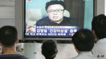 Ljudi stoje pred ekranom sa slikom iz programa južnokorejske televizije