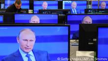 A customer walks past the TV screens in a shop in Moscow, on April 25, 2013, during the broadcast of President Vladimir Putin's televised question and answer session with the nation. AFP PHOTO / ANDREY SMIRNOV (Photo credit should read ANDREY SMIRNOV/AFP/Getty Images)