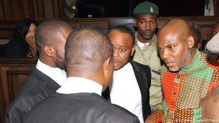 Nnamdi Kanu stands speaking to his lawyers in court