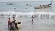People pulling small boats to the shore and wading through the sea People pulling small boats to the shore and wading through the sea