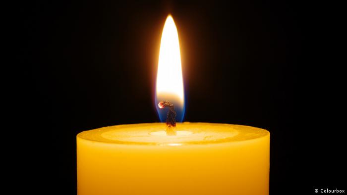 A close-up image of a flame burning a white candle.