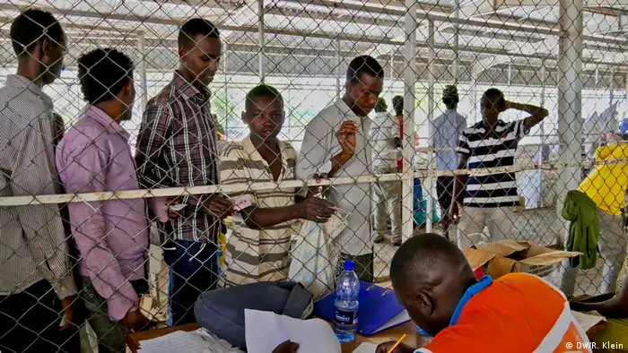 Hacer colas para recibir las respectivas raciones demora hasta cinco horas. Los trabajadores son aislados por una malla de alambre para protegerlos de la violencia que puede surgir ante la desesperación de la escasez y el hambre. 