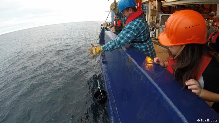 A crew member takes a water sample out of the ocean with a bucket (Eva Brodte)