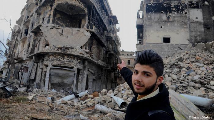 Ein Mann deutet in Aleppo auf eine Ruine