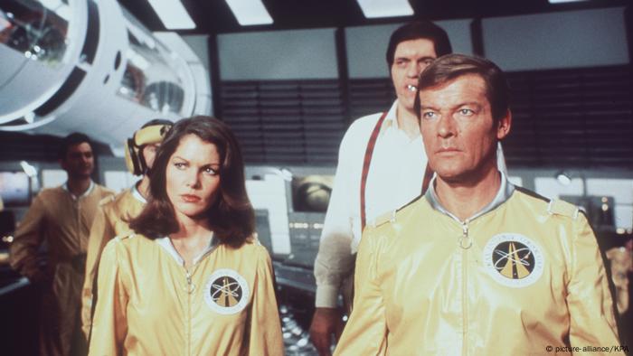 Roger Moore als James Bond in Moonraker im Raumschiff in gelbem Anzug. Neben ihm Lois Chiles als Holly Goodhead. (Foto: picture-alliance/KPA)