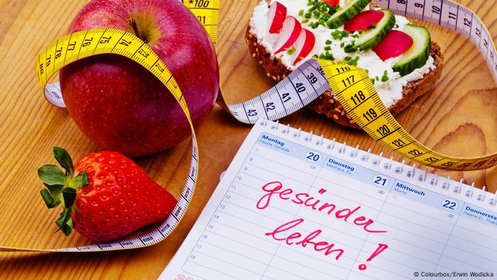 Apple, tape measure, bread with vegetables and a calendar with a good resolution to adopt a healthy lifestyle written on it