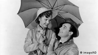 Debbie Reynolds und Gene Kelly unter einem Regenschirm im Film Singing In The Rain