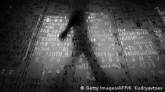 A person's shadow in front of a wall with encrypted text