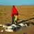 Žena s djetetom u Somaliji prolazi pored kadavera koza 