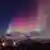 Northern lights illuminate the sky over snow-covered mountains in Norway