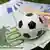 Euro bills under a mini soccer ball