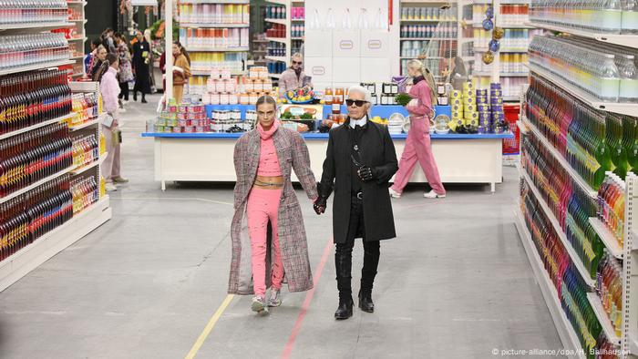 Karl Lagerfeld and Cara Delevigne on a catwsalk that looks like a supermarket aisle. (picture-alliance/dpa/H. Ballhausen )