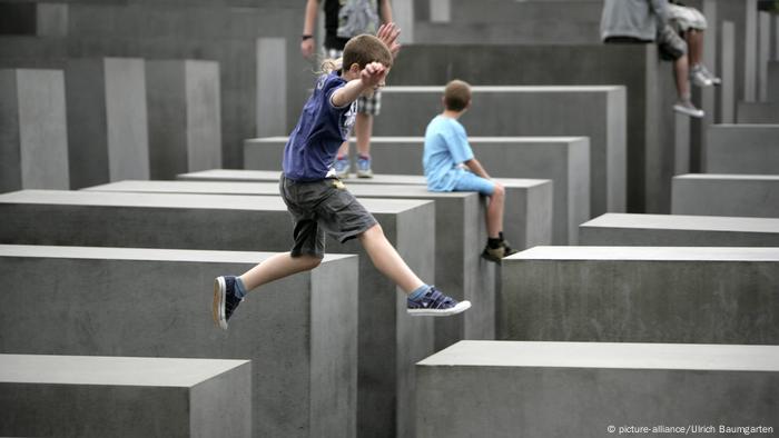 A boy jumps between concrete slabs (stelae) at the Memorial to the Murdered Jews of Europe in Berlin.  (Picture-Alliance / Ulrich Baumgarten)