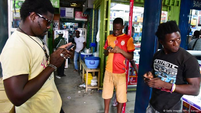 Three people standing looking into their cellphones