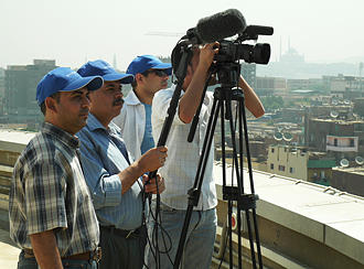 Vier Fernsehjournalisten filmen auf einem Dach.
