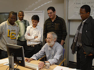 Teilnehmer mit Projektmanager vor einem Computer.