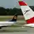 A plane of the German airline Lufthansa passing behind one of the Austrian Airlines