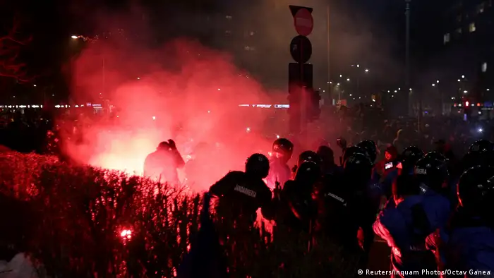 A flare throw by protesters lands near Romanian police