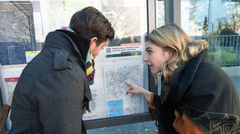 An der Haltestelle studieren Lisa und Nico den Plan mit den Bus- und Bahnlinien.