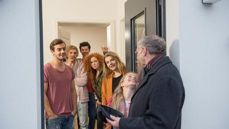 Eine Personengruppe unterhält sich an der Haustür.