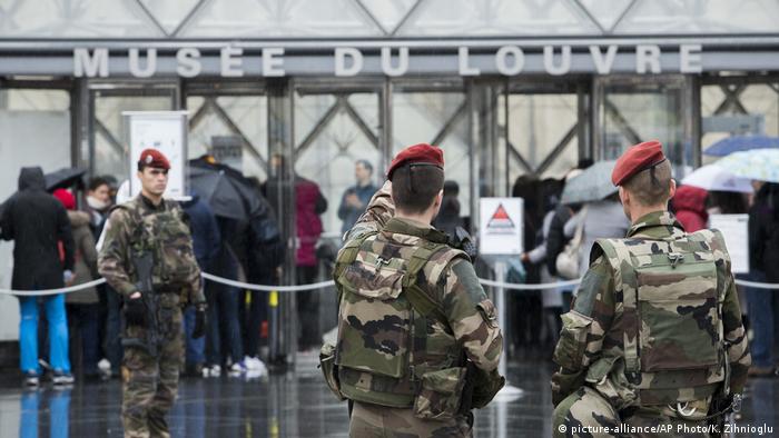 Soldiers stand guard outside the Louvre and point to the building (picture-alliance/AP Photo/K. Zihnioglu)