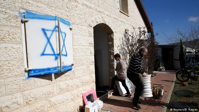 Eine Frau und ein Mann tragen Gegenstände aus einem Haus. Auf einem Fensterladen ist die israelische Fahne gemalt. (Foto: Reuters/B. Ratner)