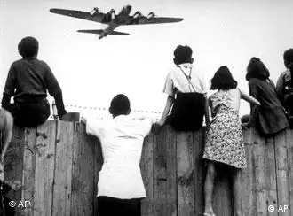 An historic photo or people watching an airlift plane fly overhead