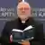 Catholic Archbishop Marx reading from his book "Das Kapital" in front of a banner promoting the title